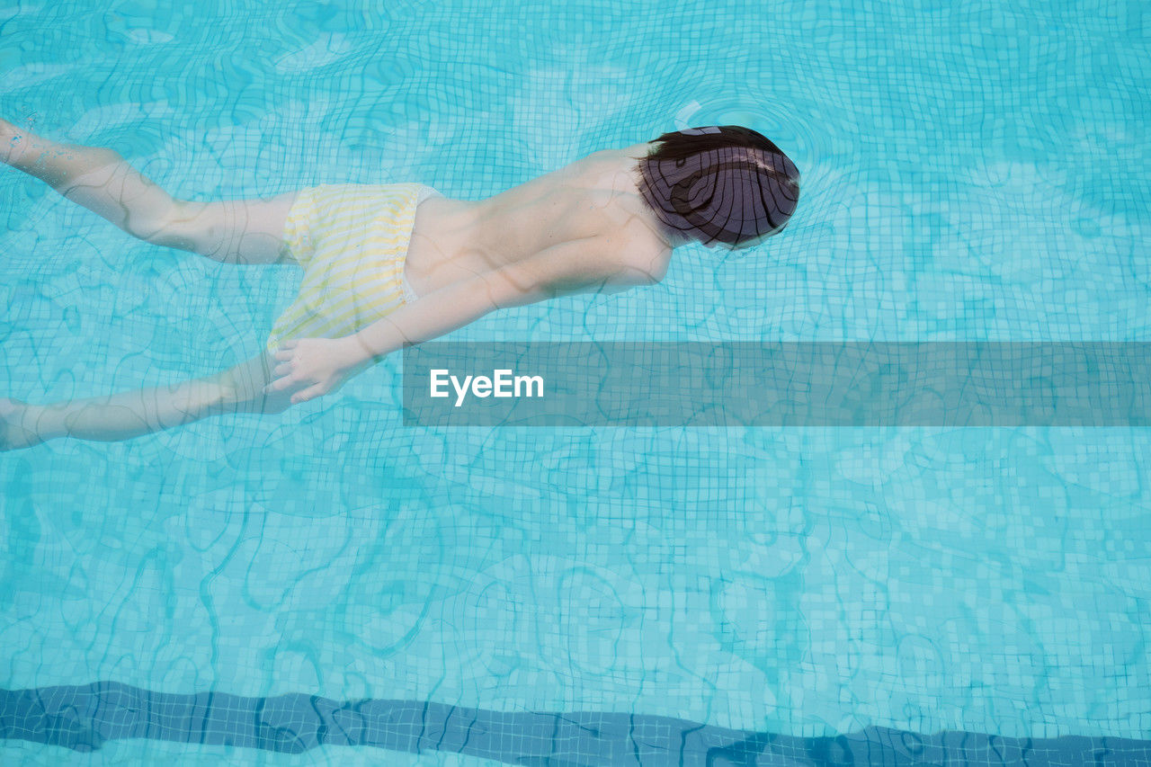 full length of shirtless boy swimming in pool