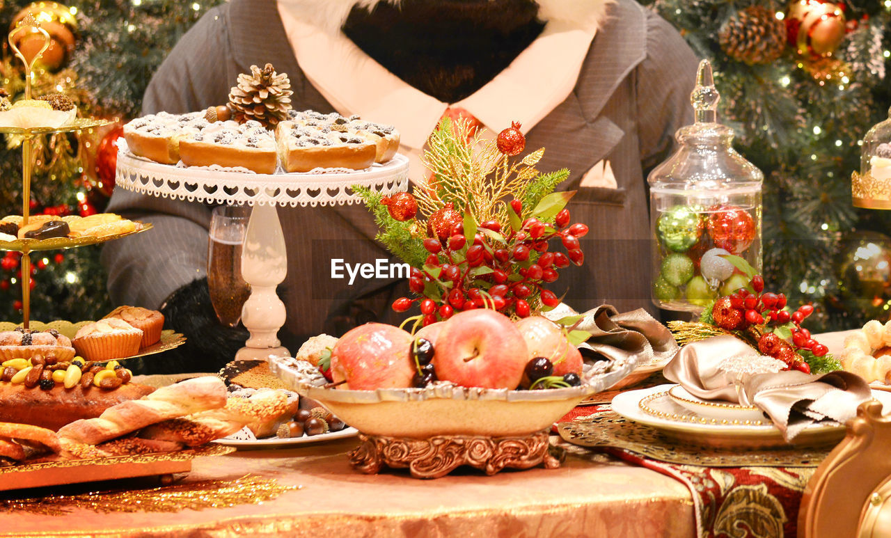 Midsection of person by table with fruits during christmas