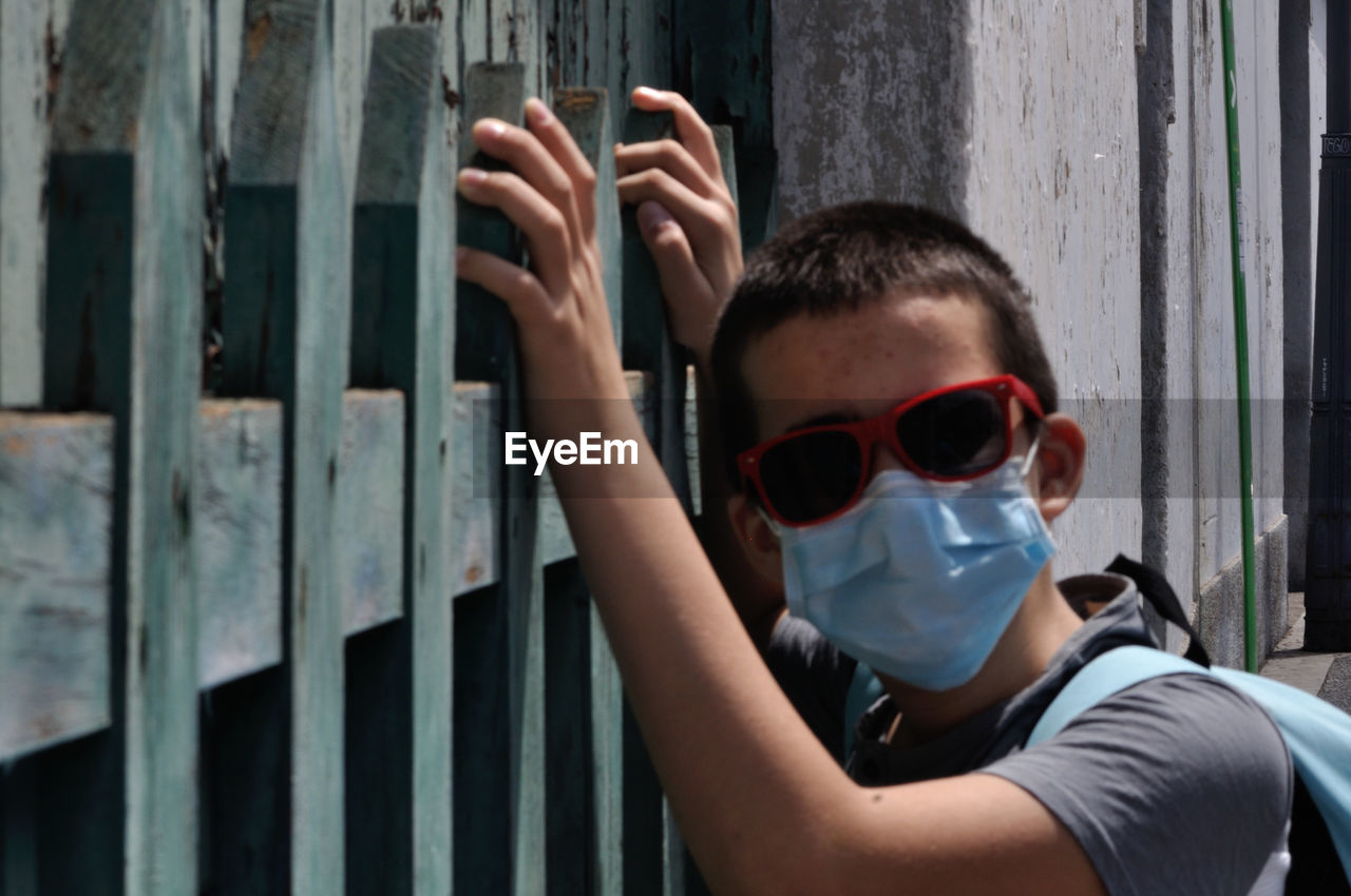 Portrait of boy wearing sunglasses standing by gate