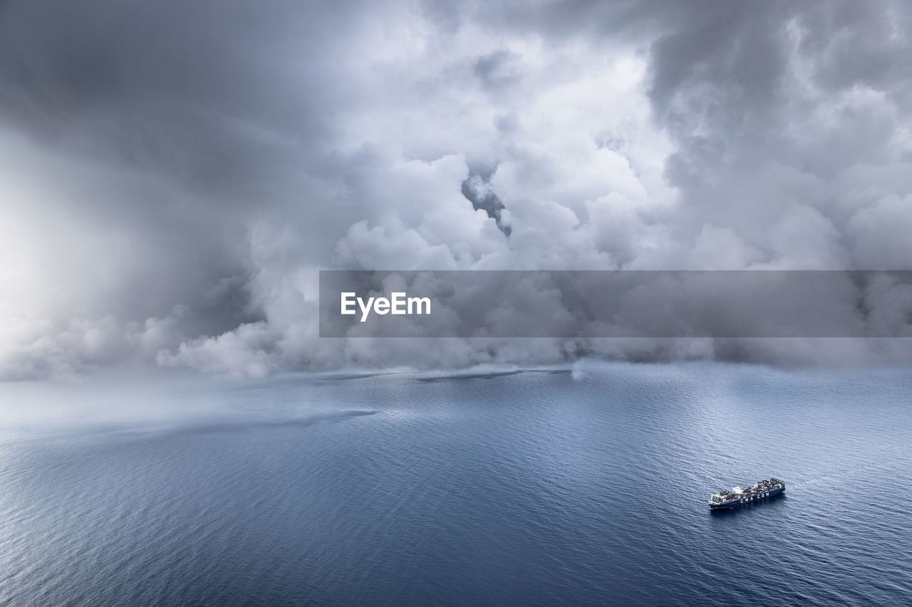 Aerial view of boat on sea against cloudy sky