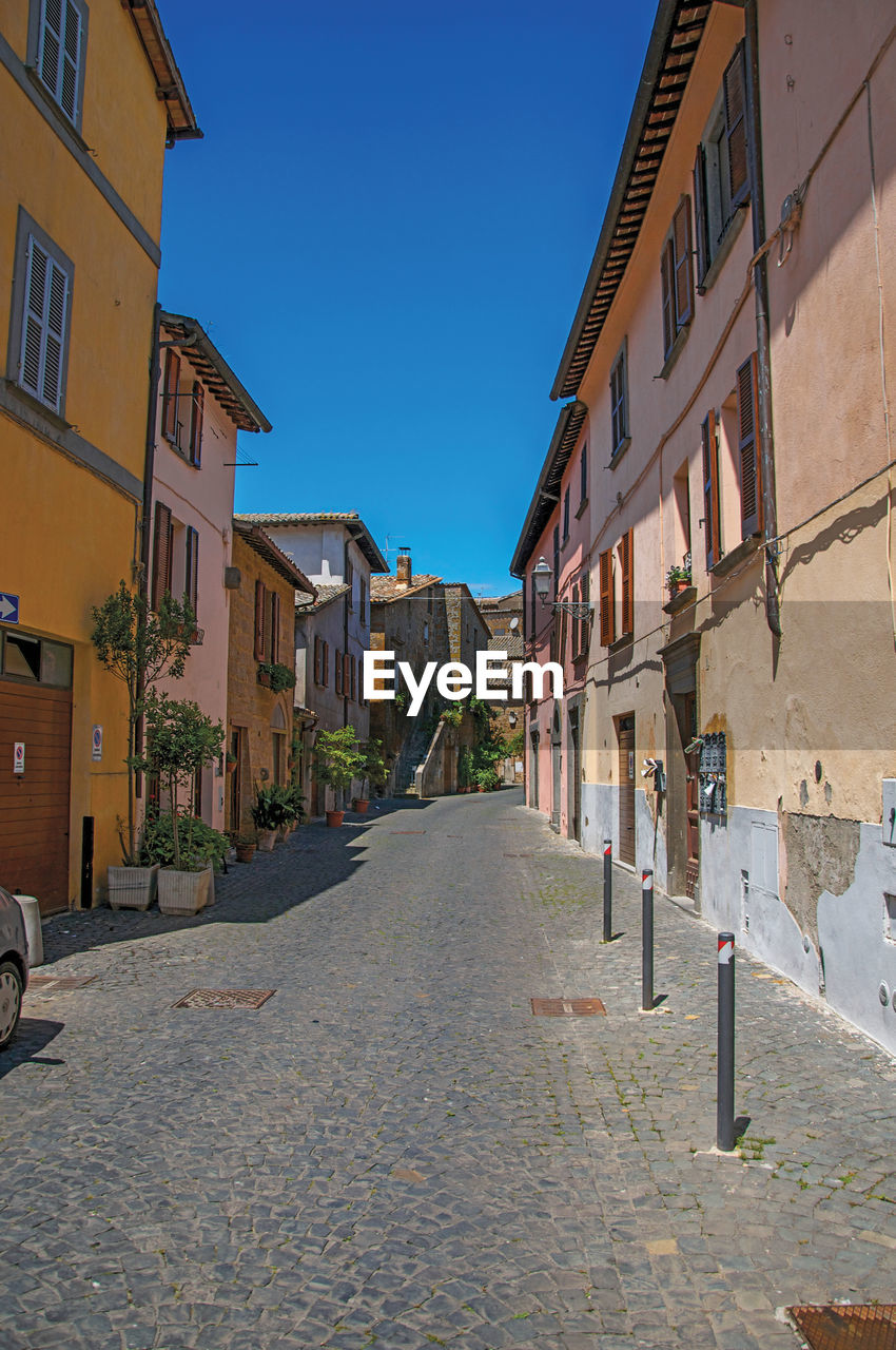 Alley with old buildings and garage under a sunny blue sky, at the town of orvieto, italy.