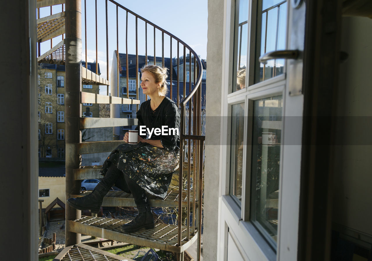 Woman sitting on fire stairs