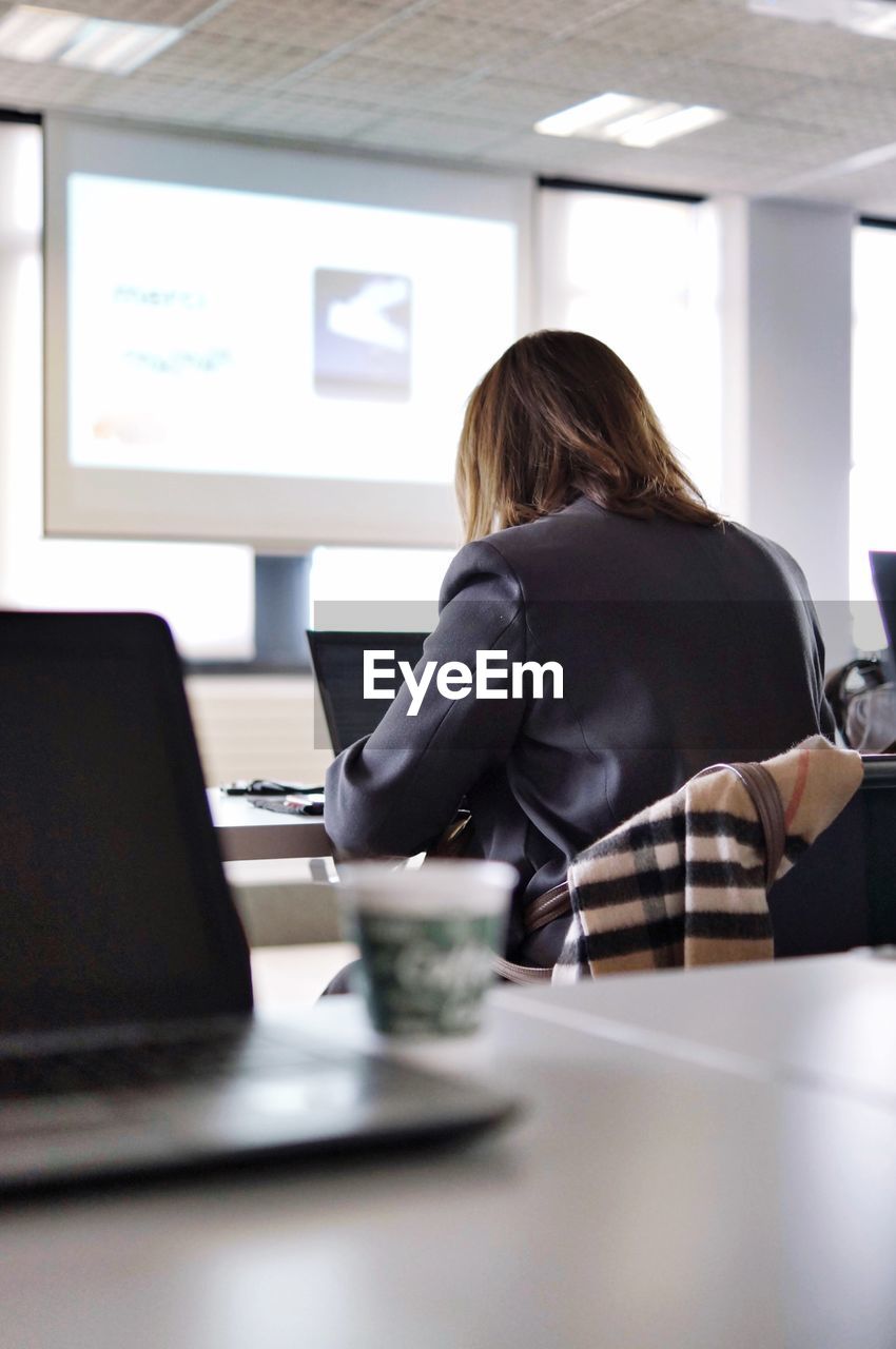 Rear view of businesswoman working on laptop in office