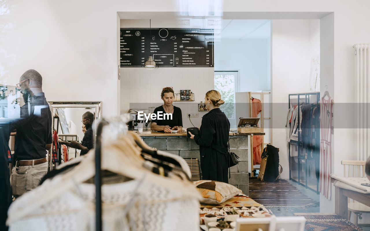 Senior owner talking to female customer in coffee shop