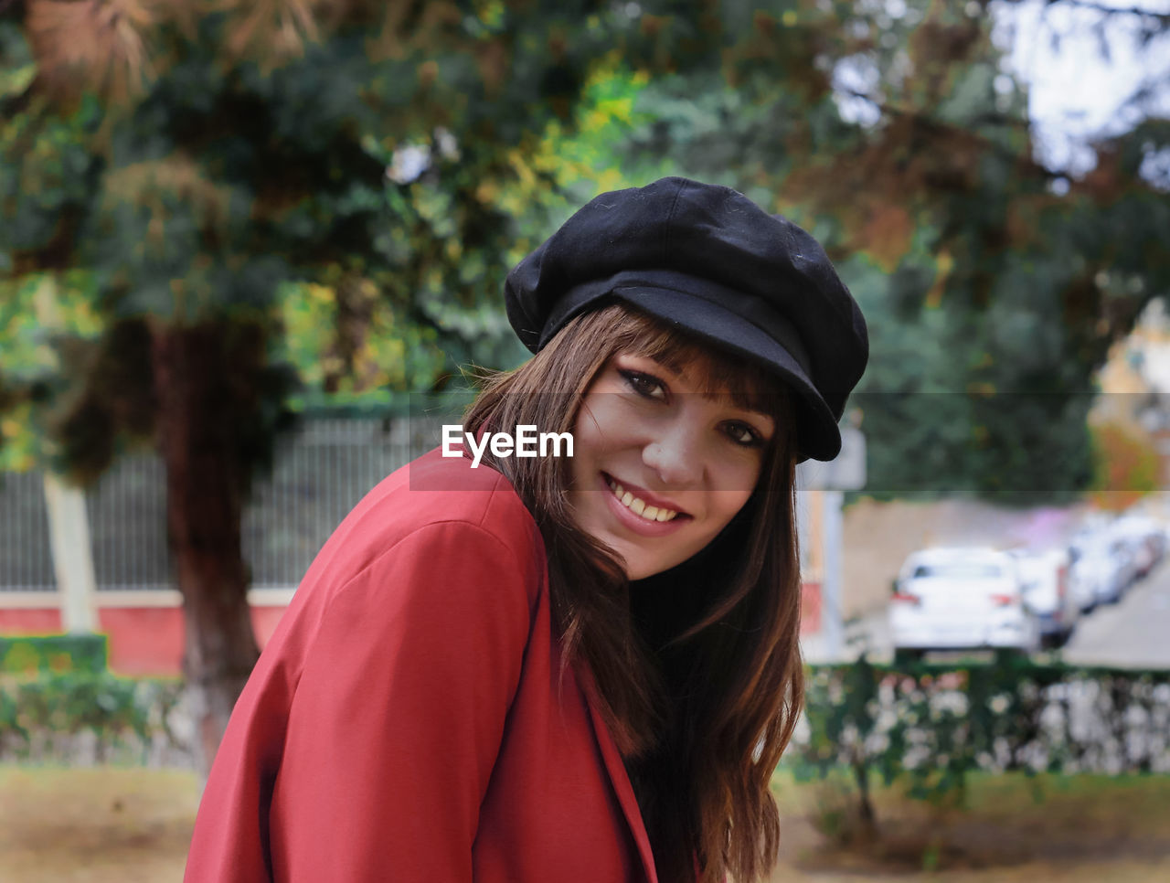 Portrait of smiling woman wearing hat sitting at park