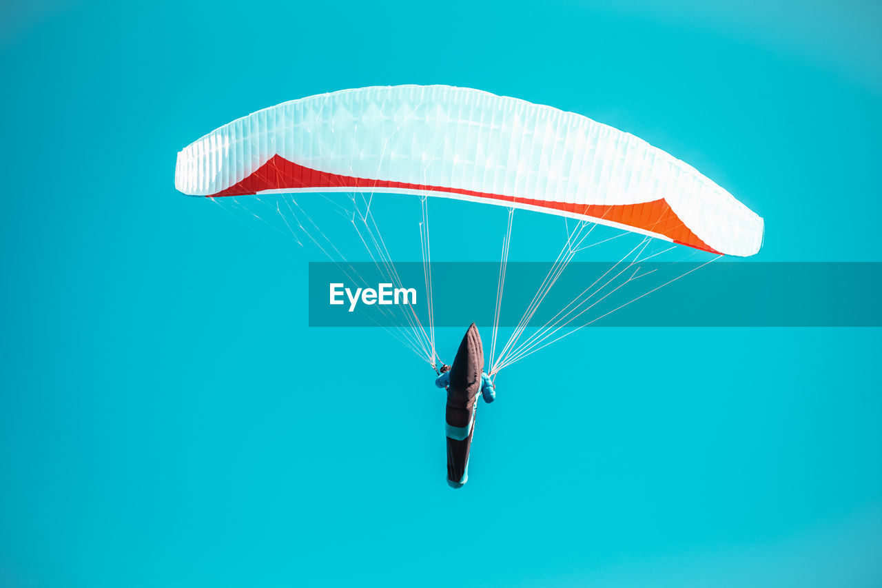 LOW ANGLE VIEW OF PERSON PARAGLIDING AGAINST BLUE SKY