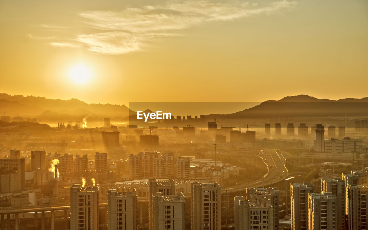 Aerial view of illuminated cityscape against sky during sunset