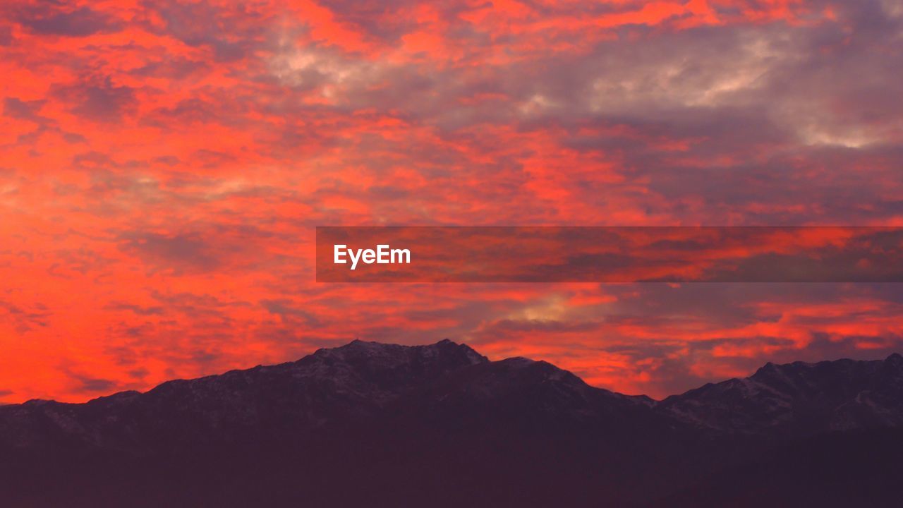 Scenic view of mountains against dramatic sky during sunset