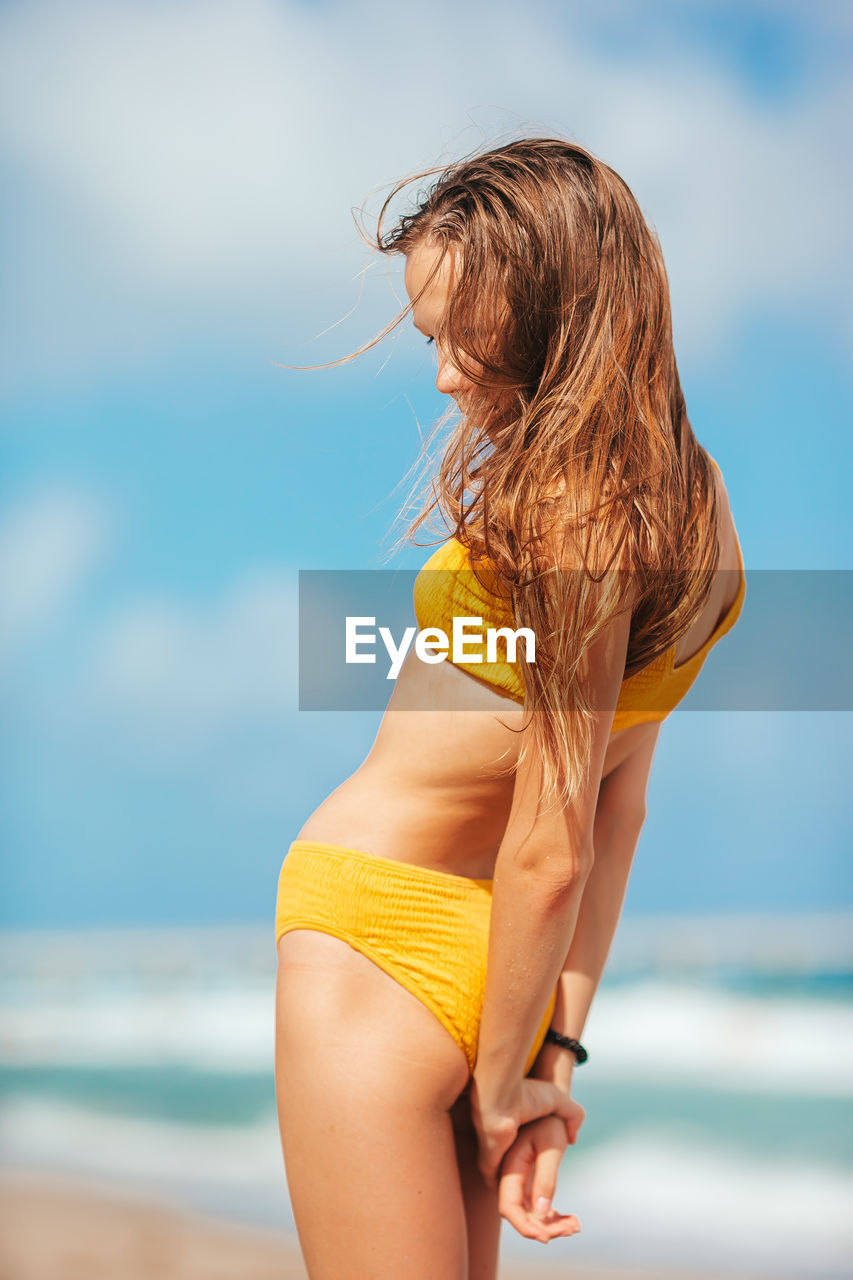 young woman in bikini while standing at beach