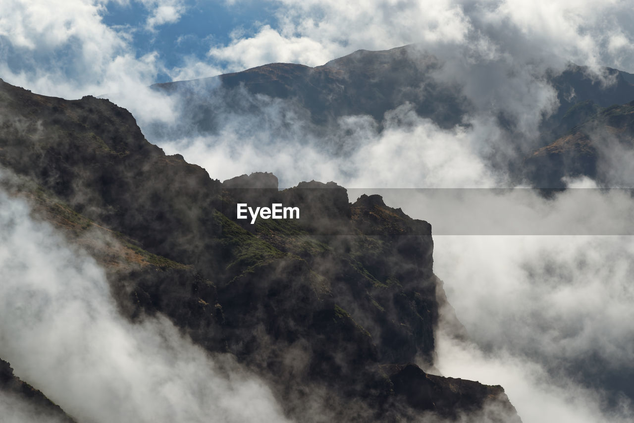 Smoke emitting from mountain against sky