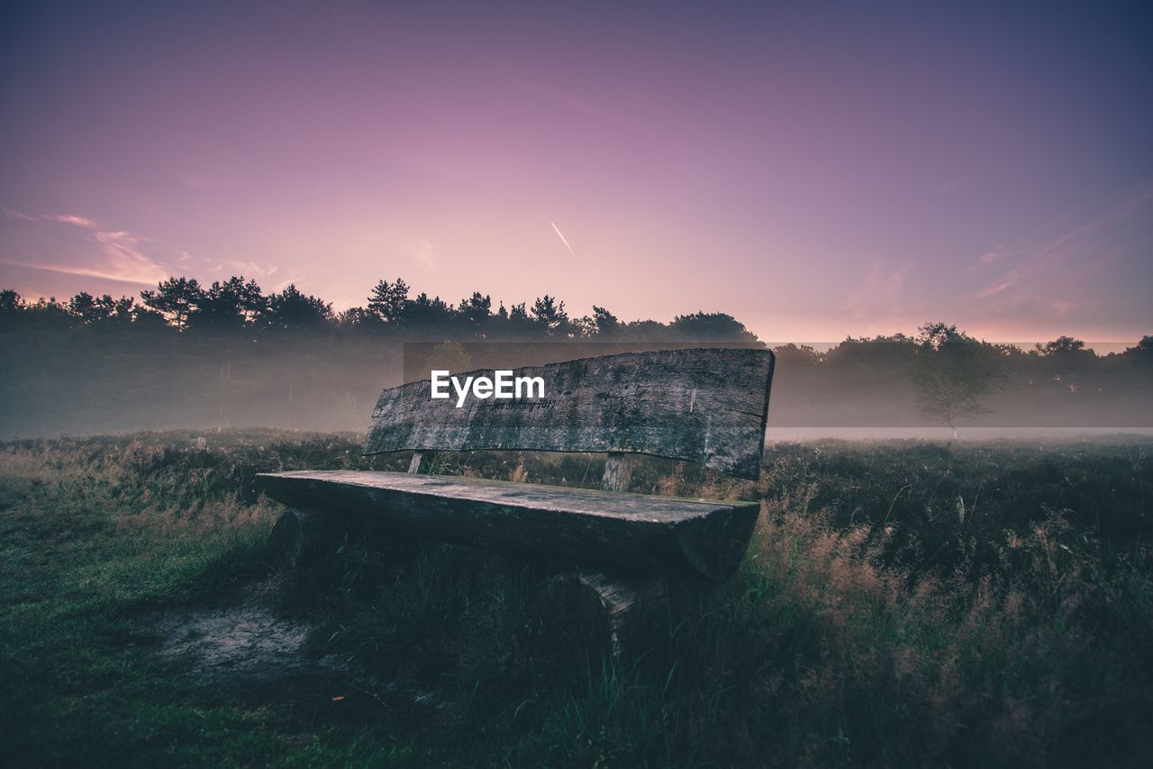 Abandoned boat on landscape against sky during sunset