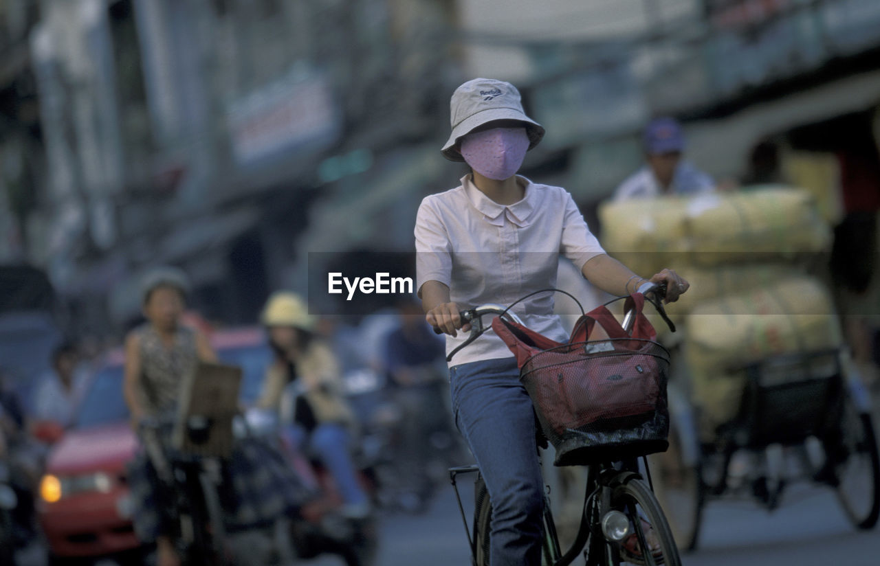 Woman wearing facial mask while riding bicycle on street