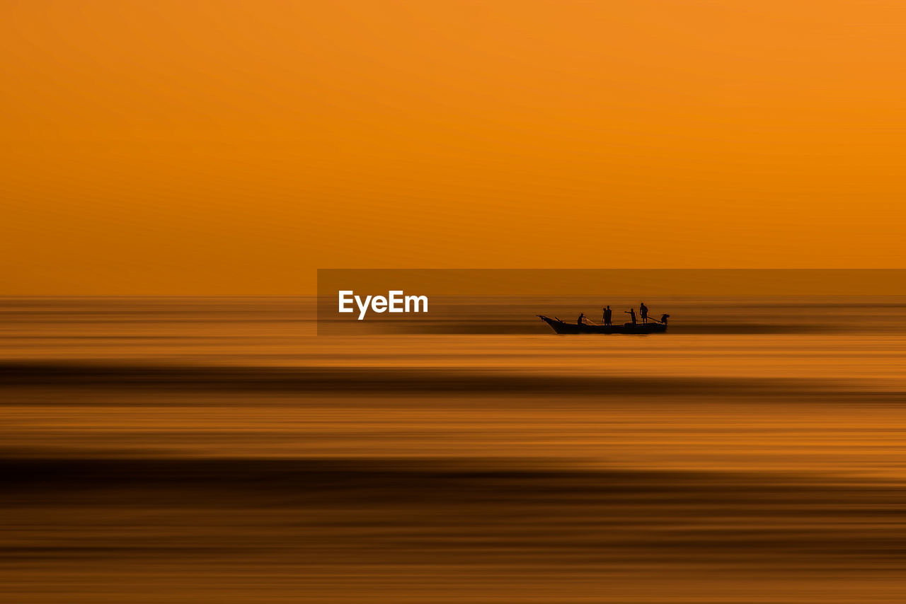 Silhouette boat on sea against orange sky