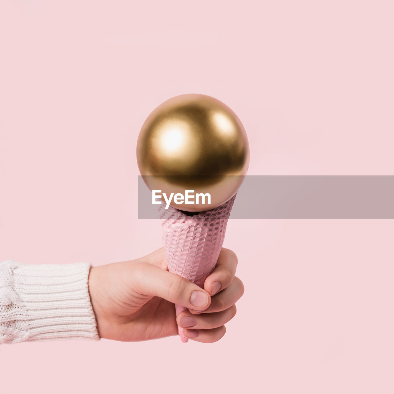 CLOSE-UP OF HAND HOLDING ICE CREAM AGAINST COLORED BACKGROUND