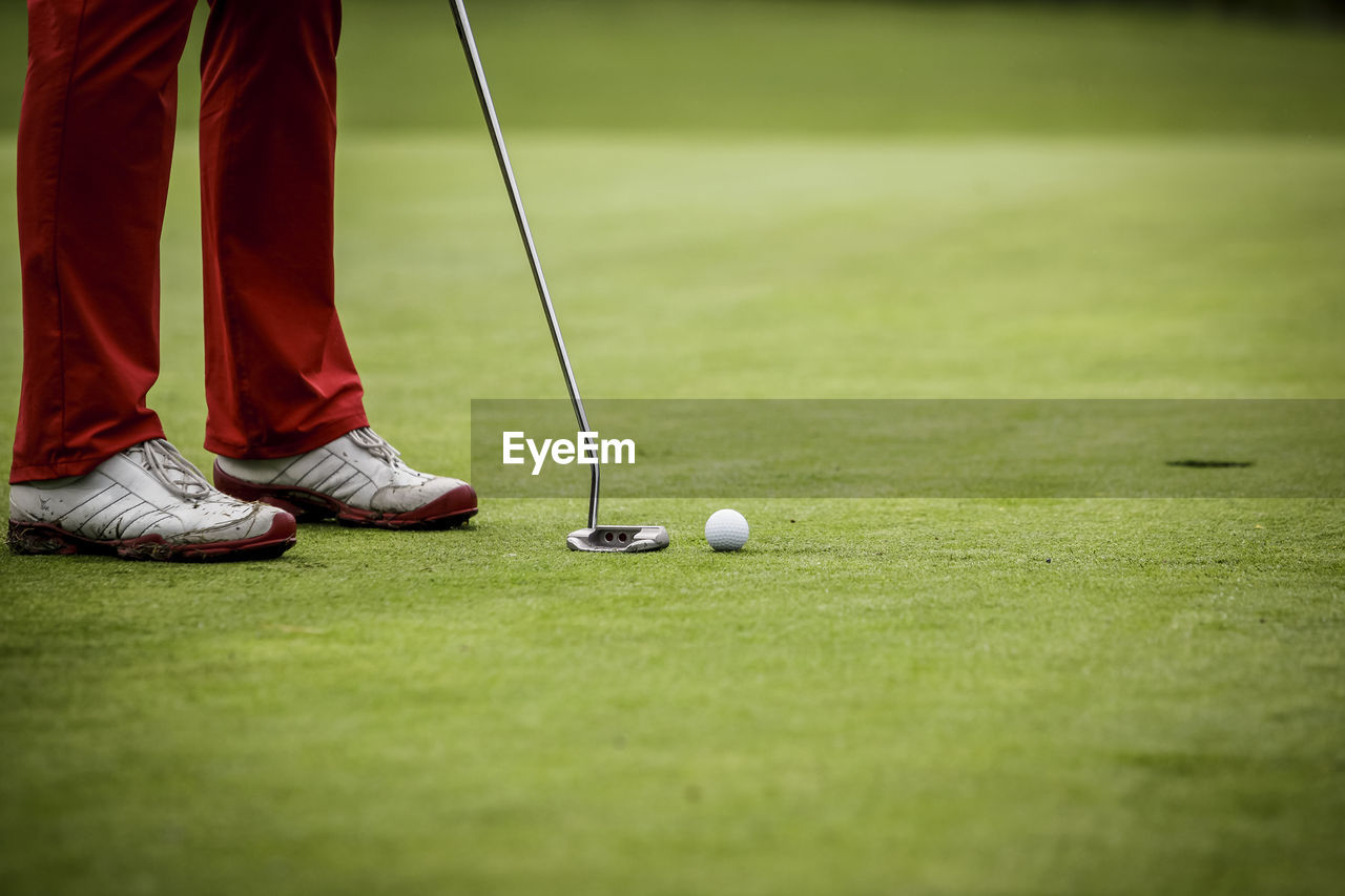 Low section of man playing golf on field