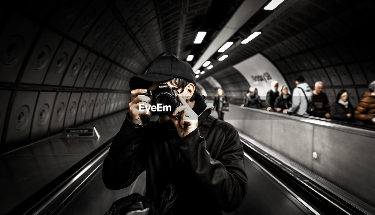 Man photographing while standing on escalator at subway station