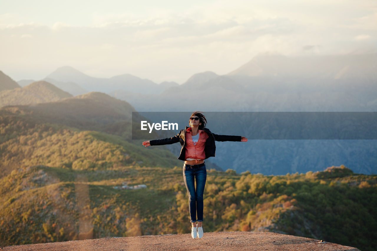 WOMAN STANDING ON MOUNTAIN AGAINST SKY