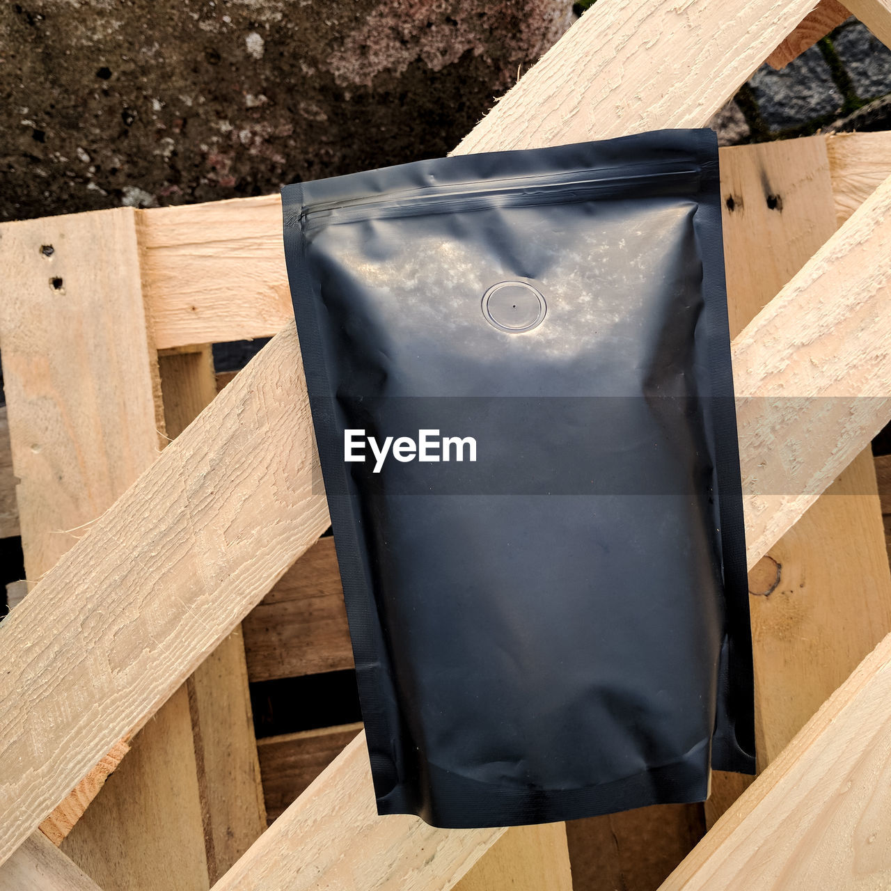 Black unbranded bag of coffee on wooden planks