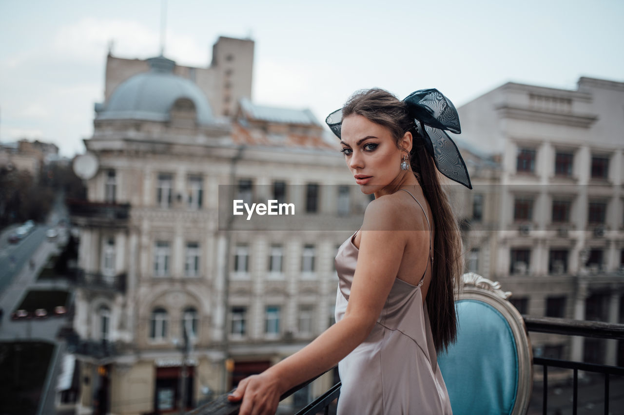 Portrait of woman standing against buildings in city