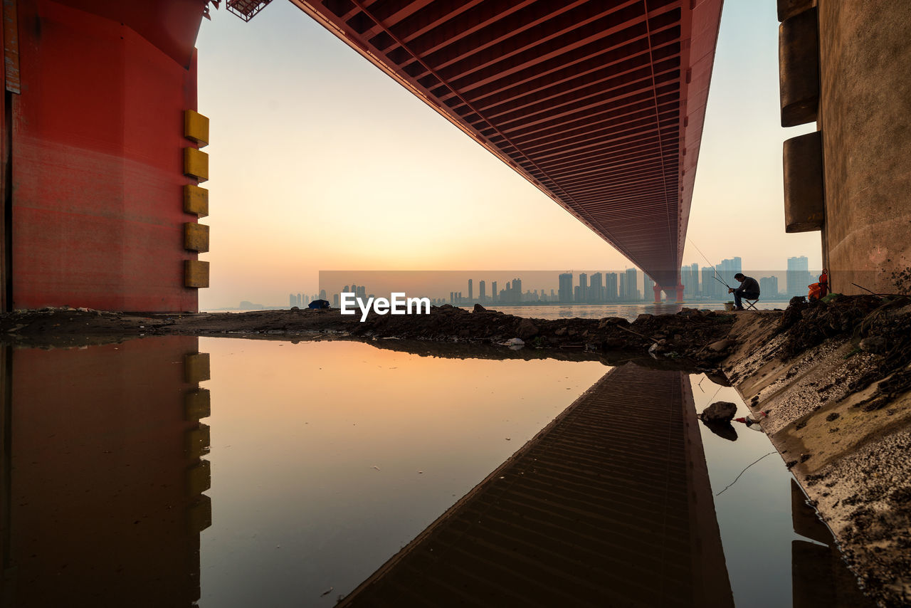 Bridge over river in city against sky