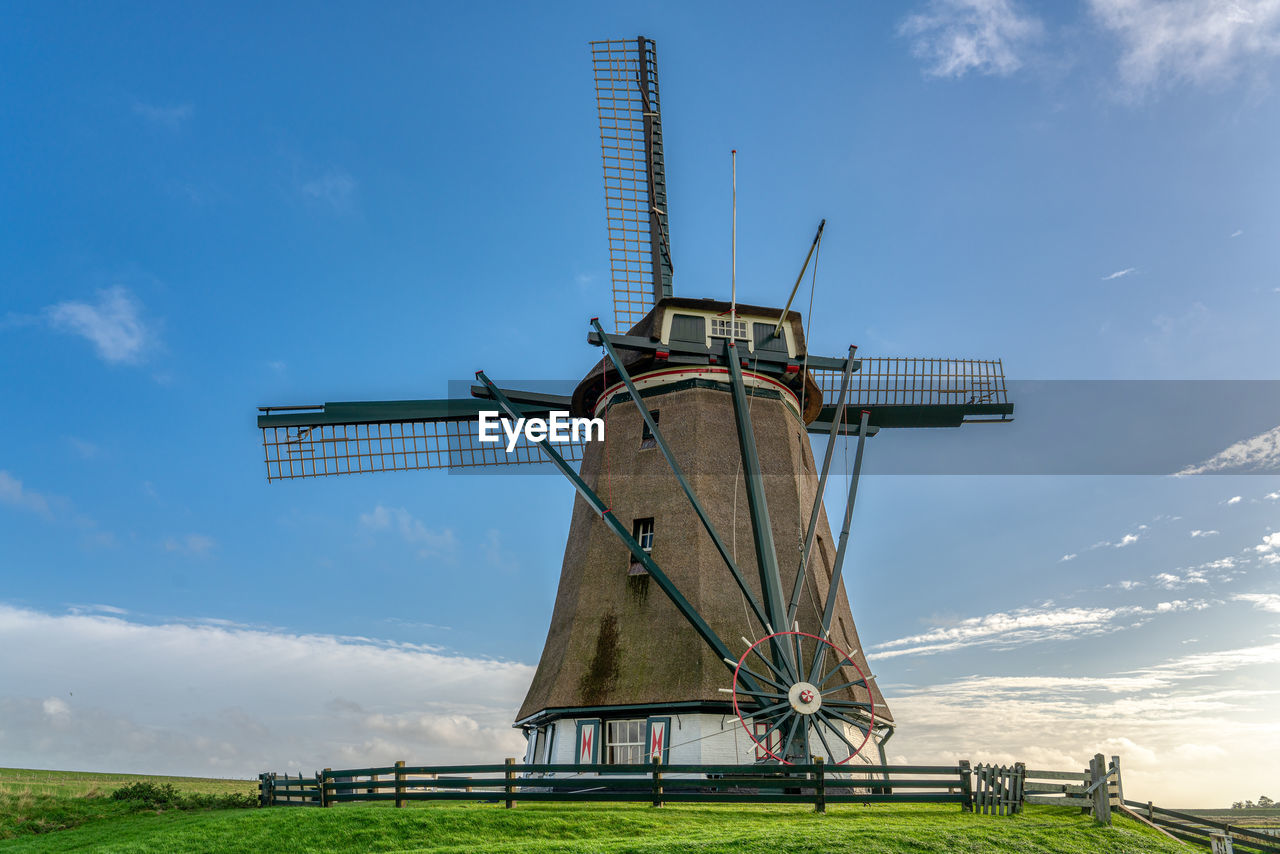 Traditional windmill on field against sky