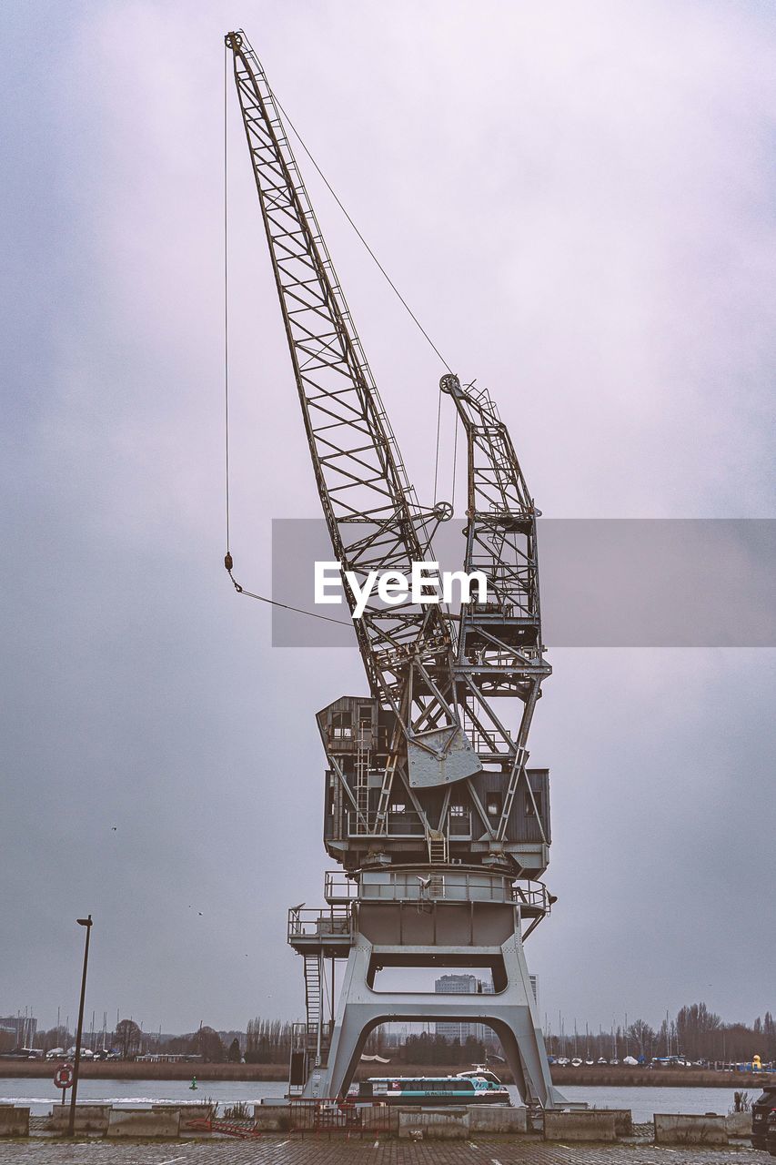 LOW ANGLE VIEW OF CRANE AT CONSTRUCTION SITE AGAINST SKY