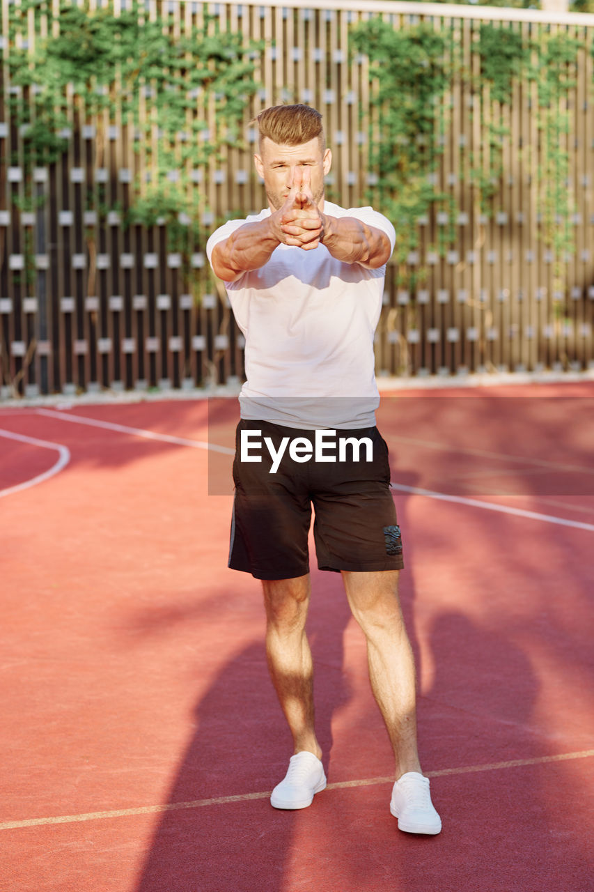 full length of young man exercising on court