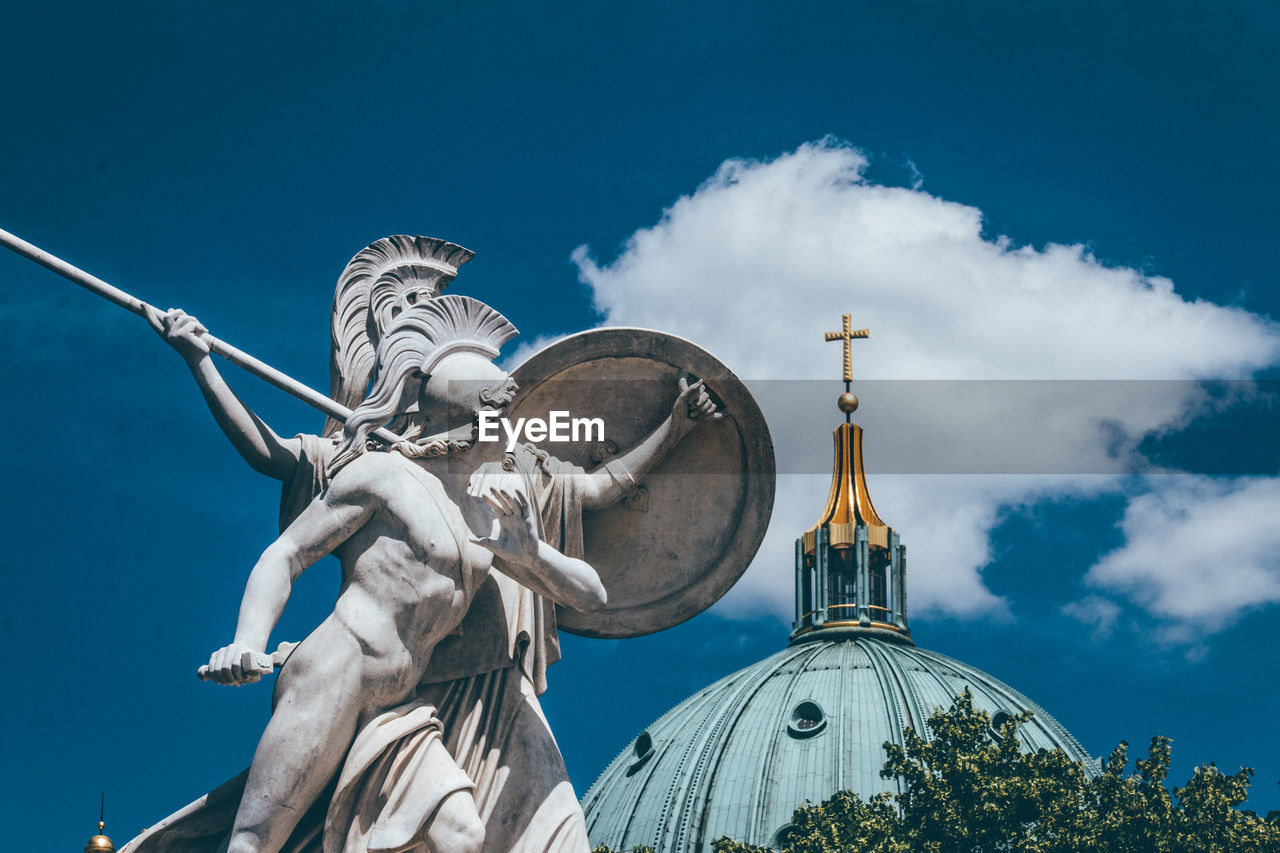 Low angle view of statue and church against sky