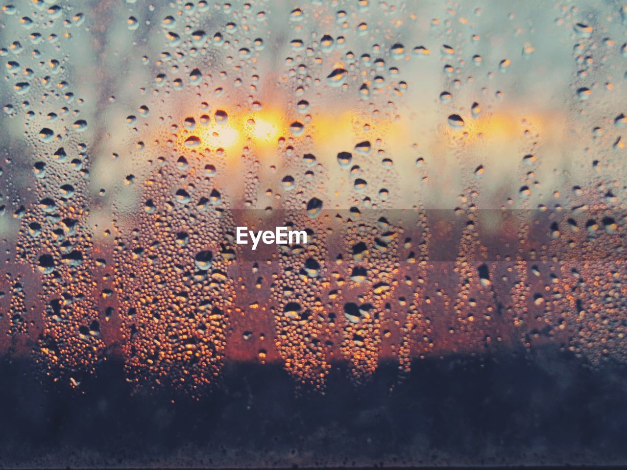 CLOSE-UP OF WET WINDOW AGAINST SUNSET SKY