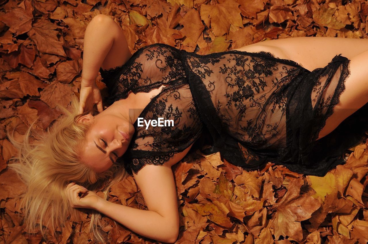 Woman in lingerie lying on leaves during autumn