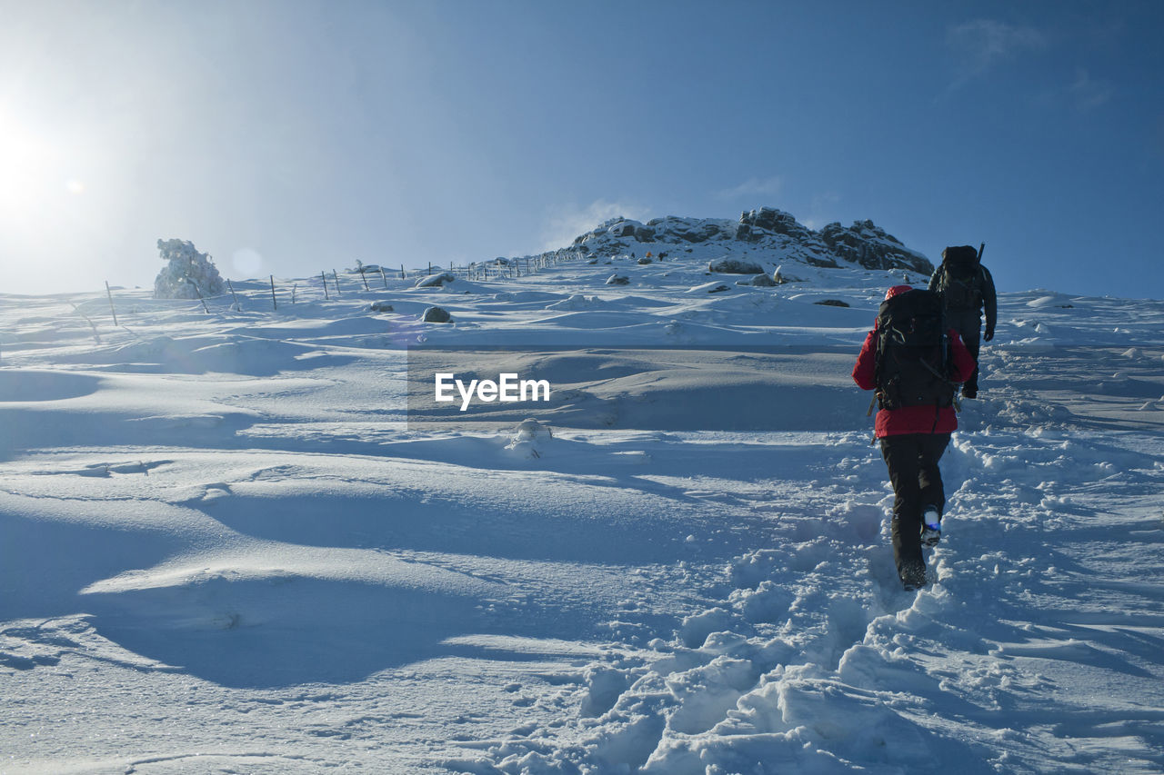 Rear view of people walking on snow covered land