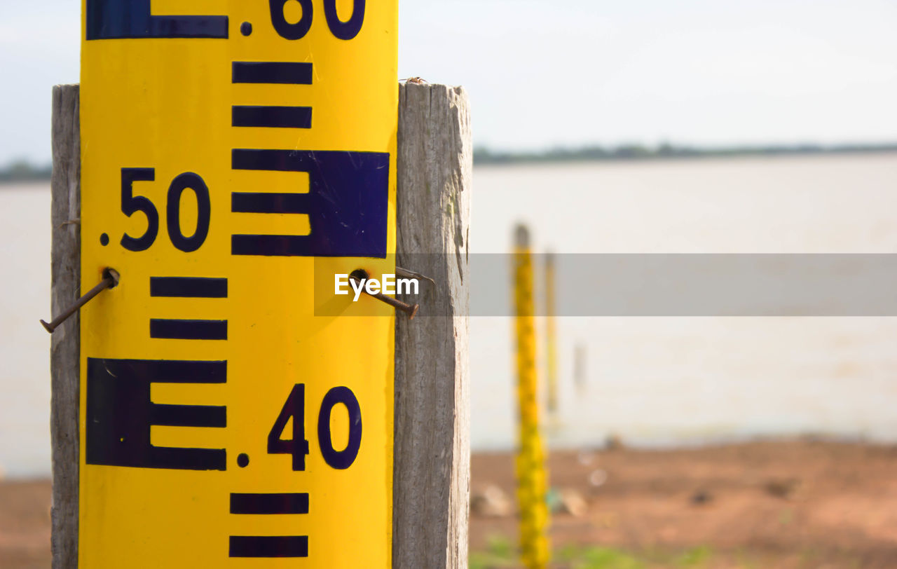 Close-up of yellow sign board against river