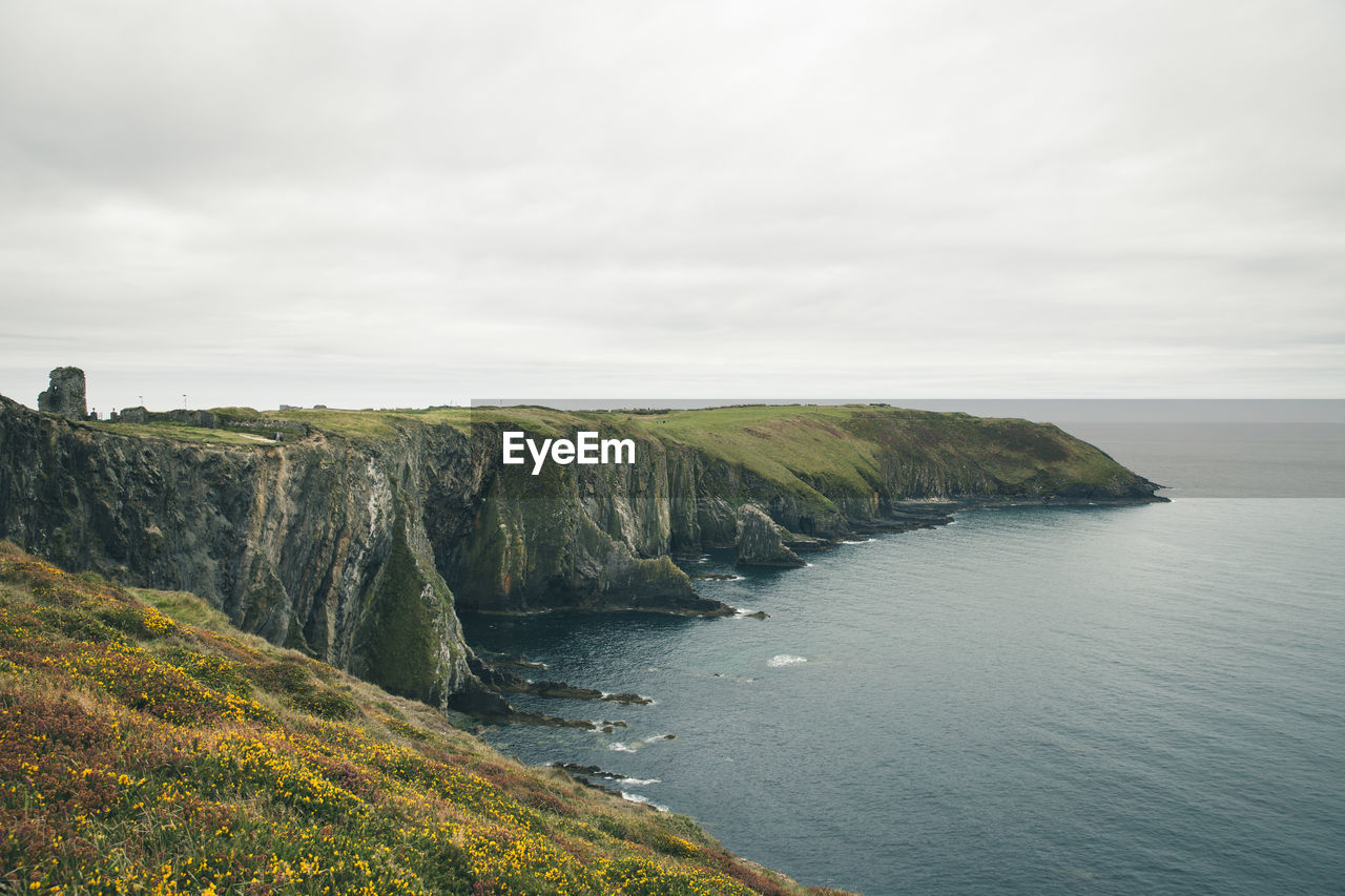 Scenic view of sea and cliff against sky