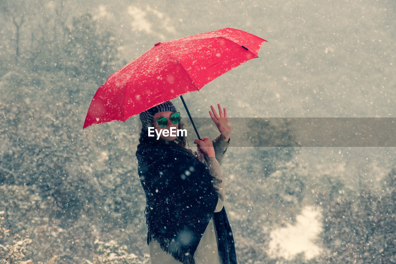 WOMAN HOLDING UMBRELLA STANDING IN SNOW