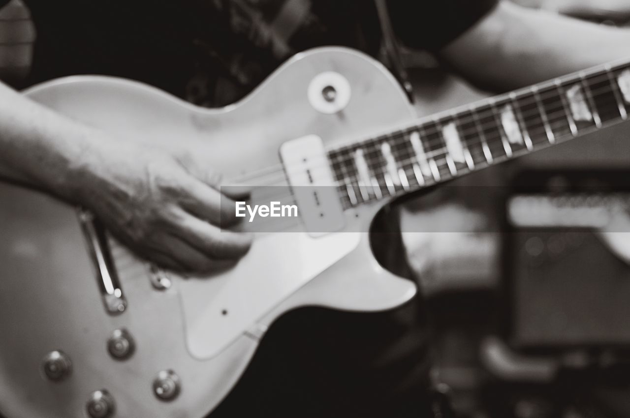 CLOSE-UP OF MAN PLAYING GUITAR IN THE MUSIC