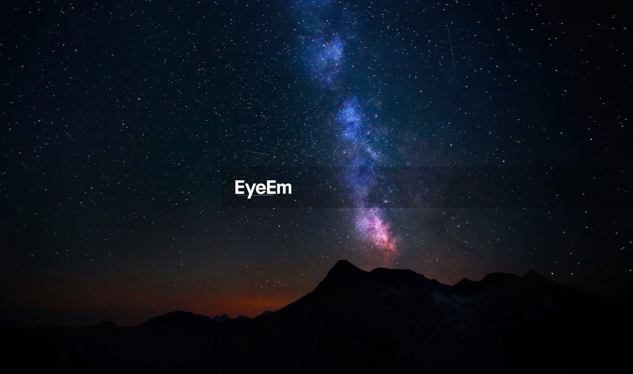 Scenic view of silhouette mountains against sky at night