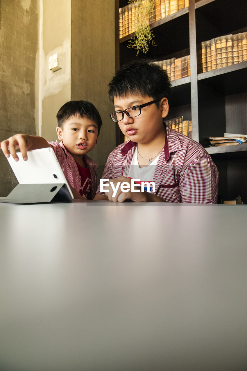 Siblings using digital tablet at home