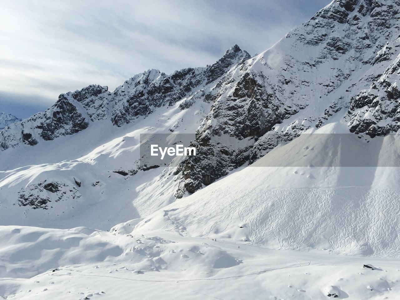 Scenic view of snowcapped mountain against cloudy sky