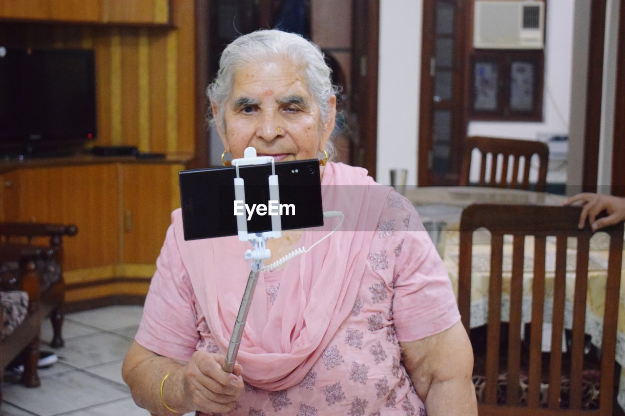 Senior woman taking selfie at home