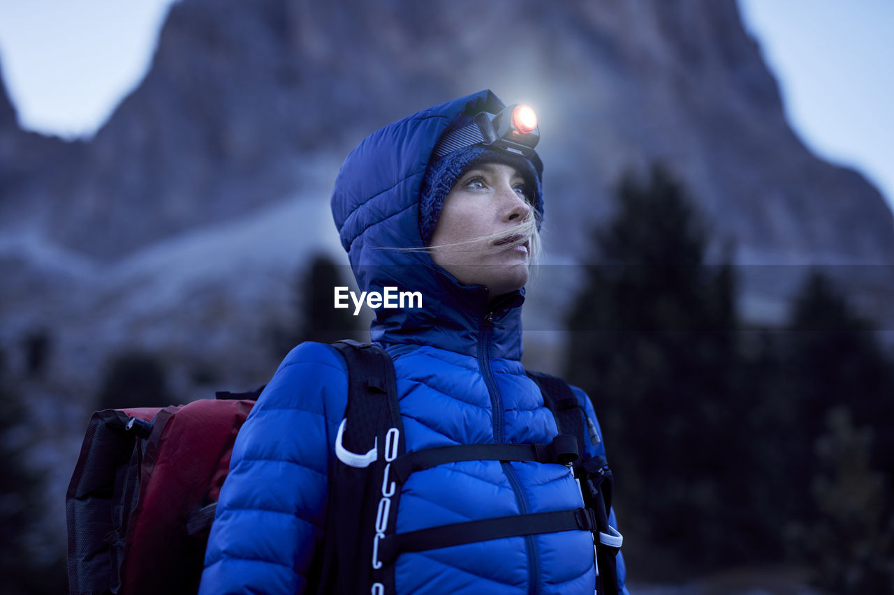 Young woman wearing headlamp at dusk in the mountains