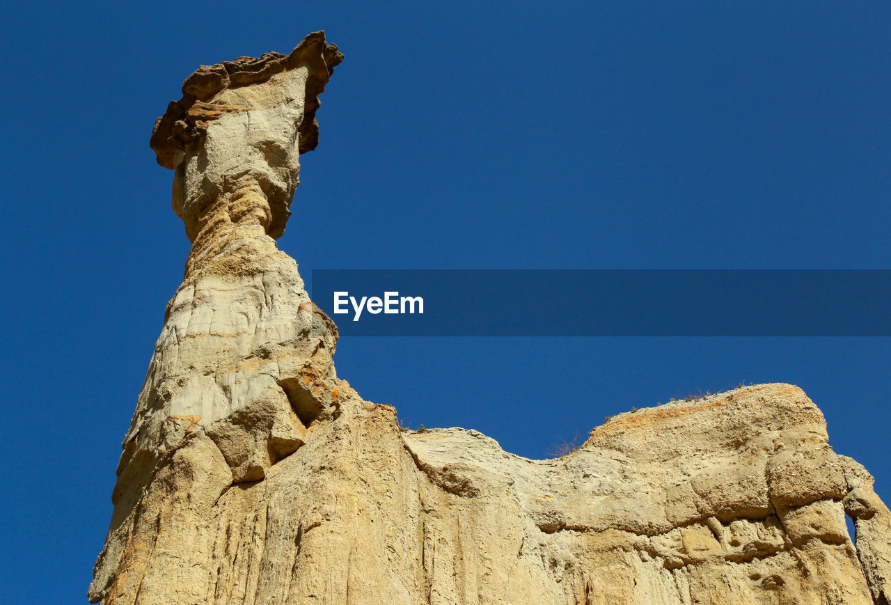 LOW ANGLE VIEW OF ROCK FORMATIONS AGAINST BLUE SKY