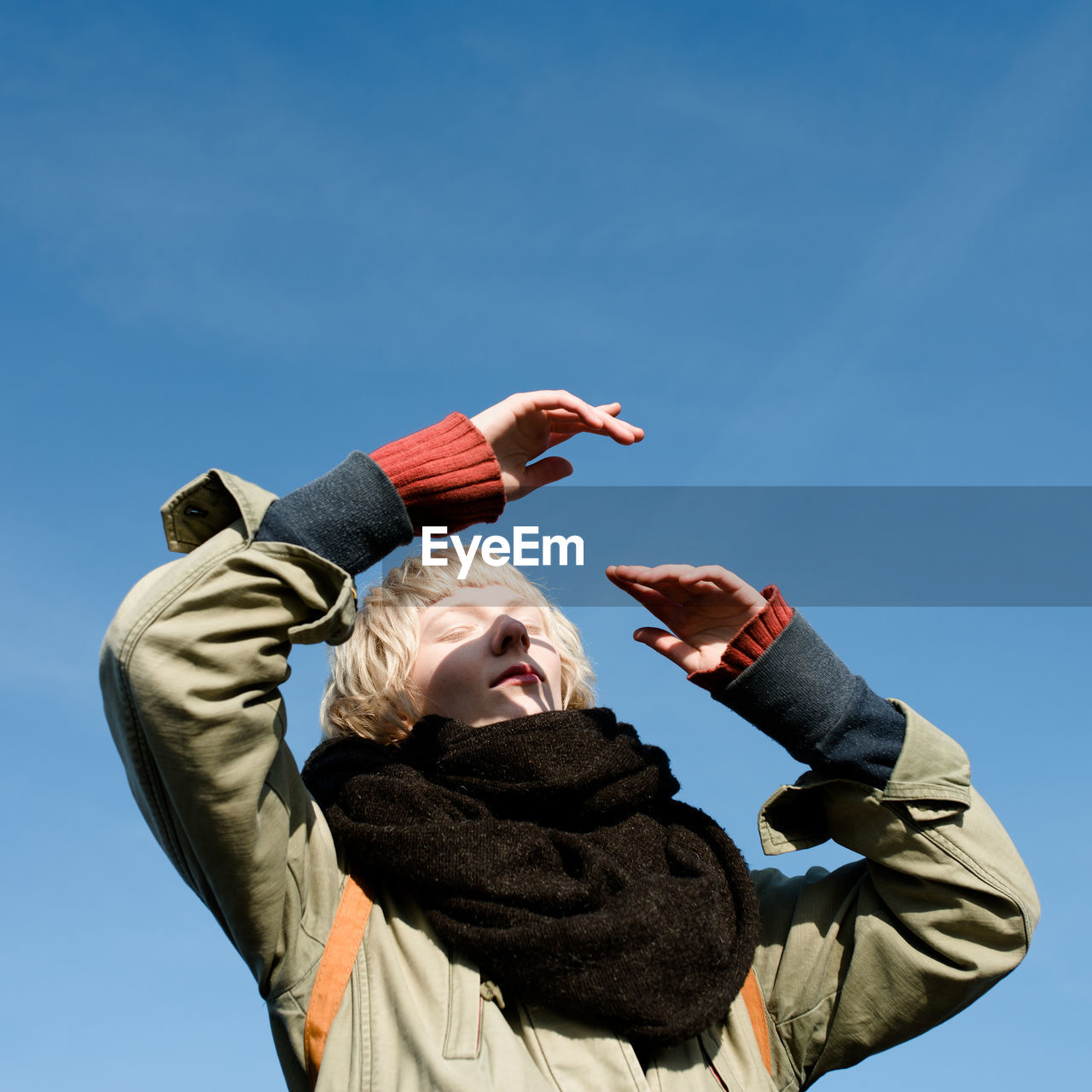 LOW ANGLE VIEW OF YOUNG WOMAN AGAINST CLEAR SKY