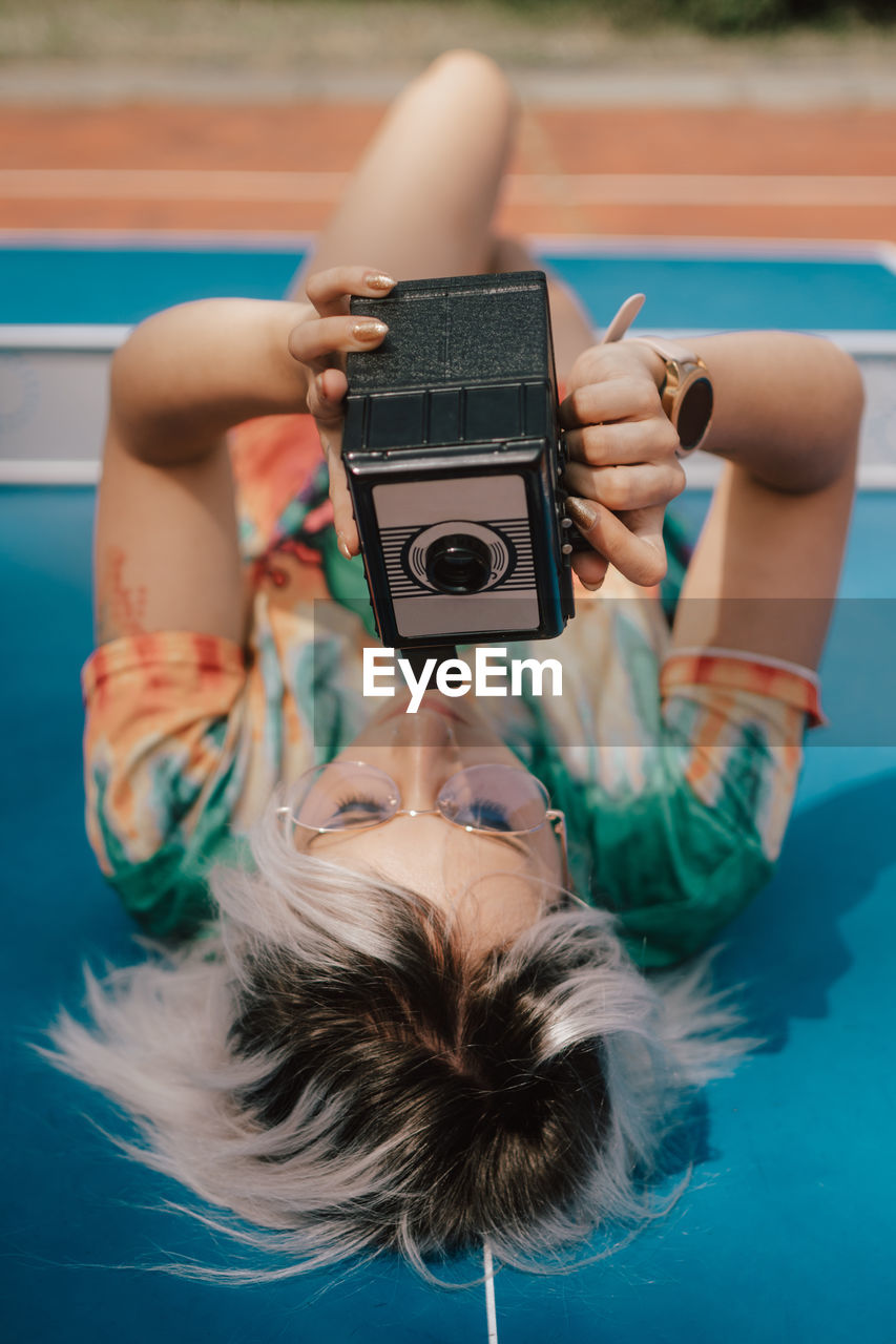 A young woman taking pictures with an analog camera in a colorful dress