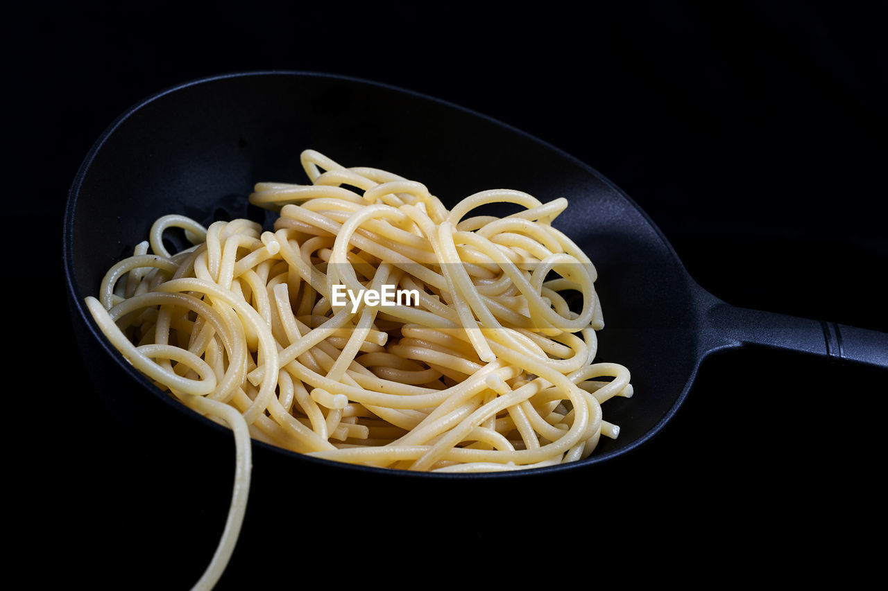 pasta, food, italian food, food and drink, black background, kitchen utensil, studio shot, indoors, spaghetti, healthy eating, freshness, wellbeing, carbonara, no people, cuisine, household equipment, produce, still life, eating utensil, vegetable, close-up