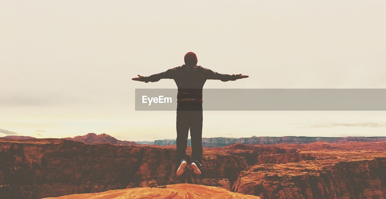 Full length of man levitating over landscape against sky