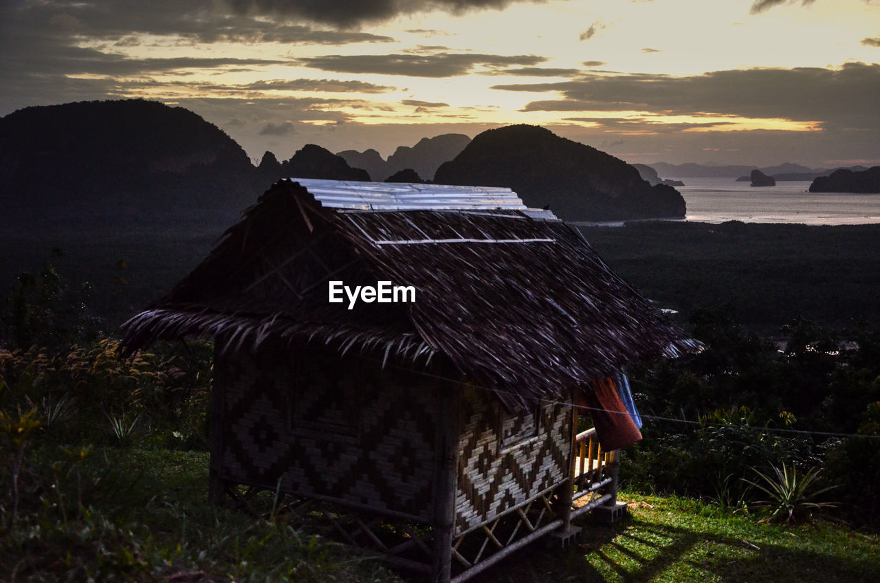 HUT ON BEACH AGAINST SKY DURING SUNSET