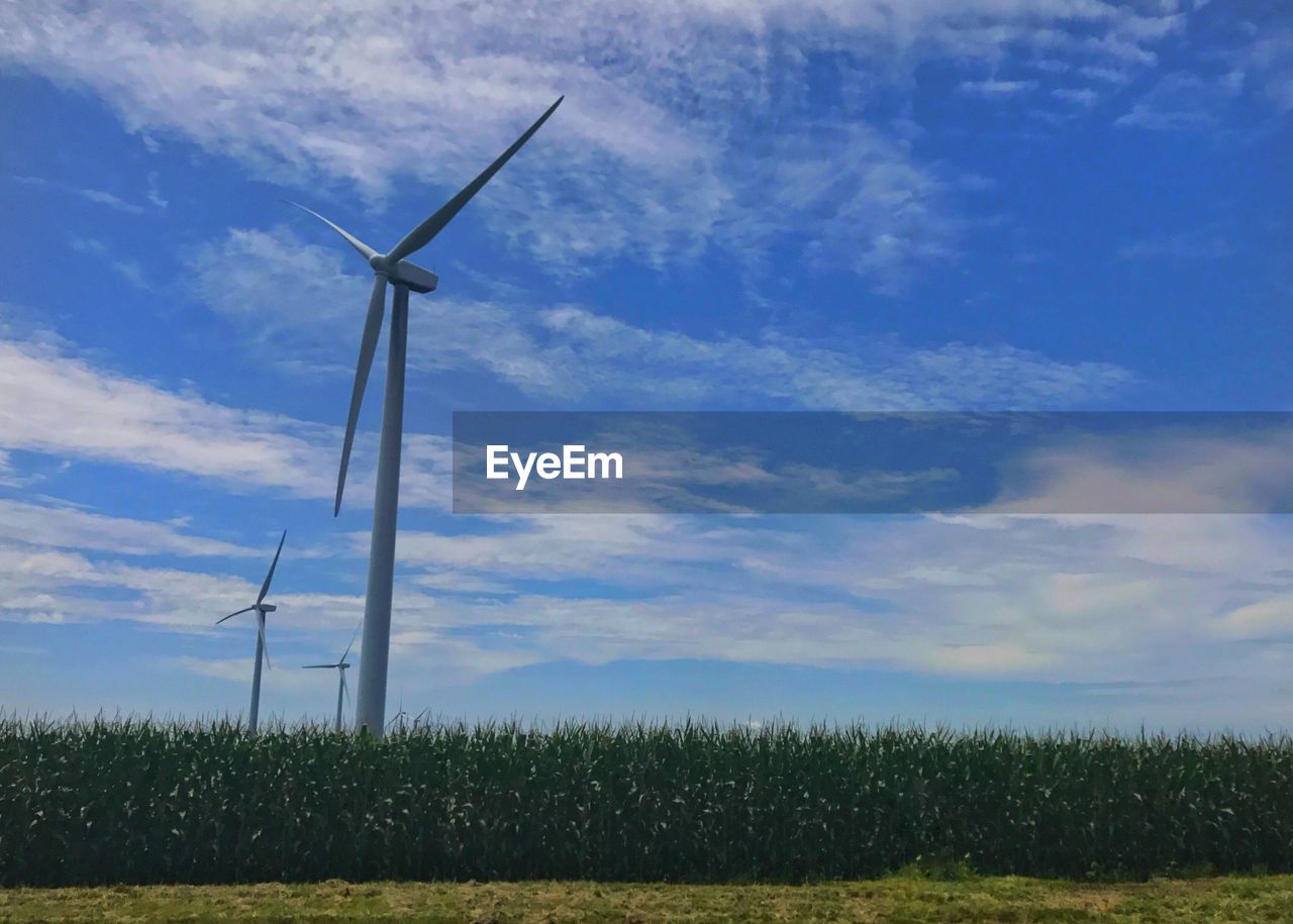 WIND TURBINES ON FIELD AGAINST SKY