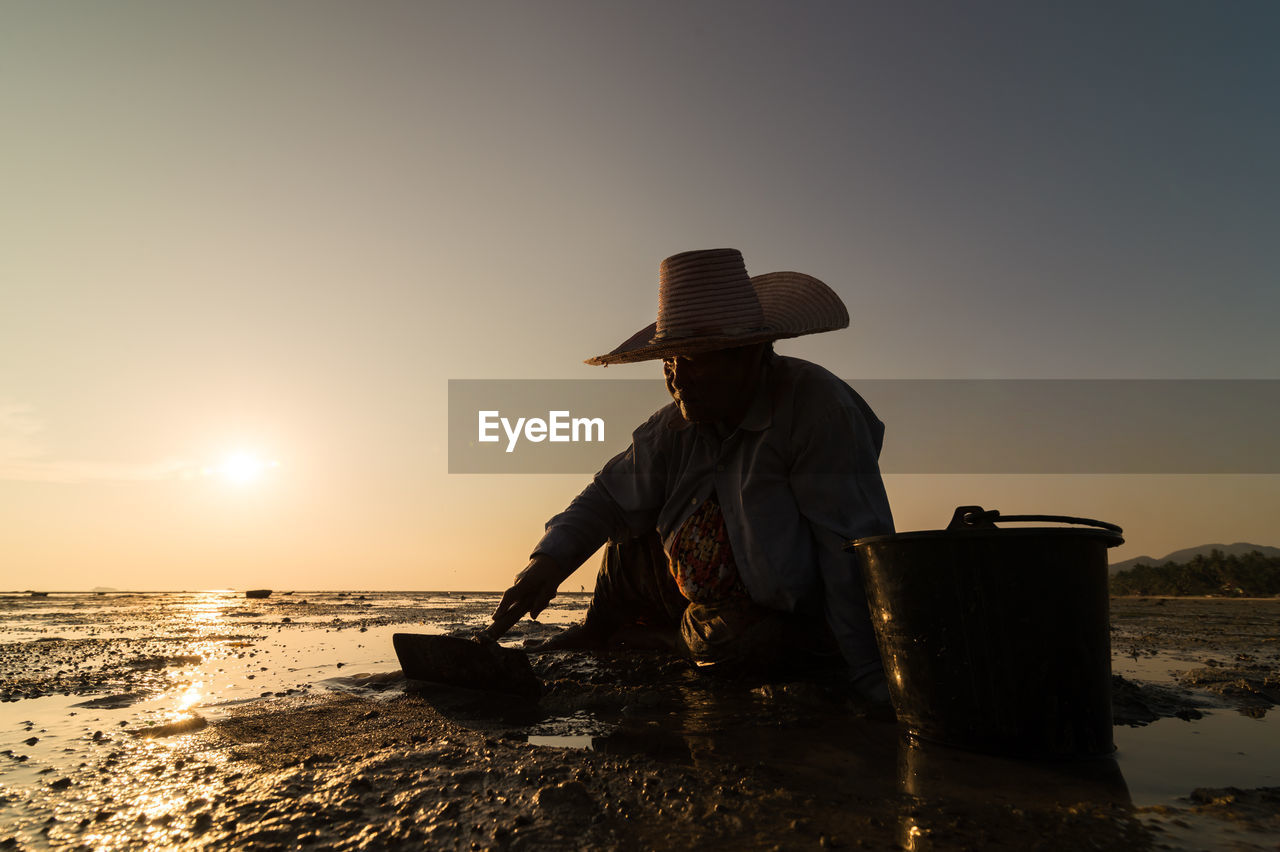 MAN IN FRONT OF SEA AGAINST SUNSET