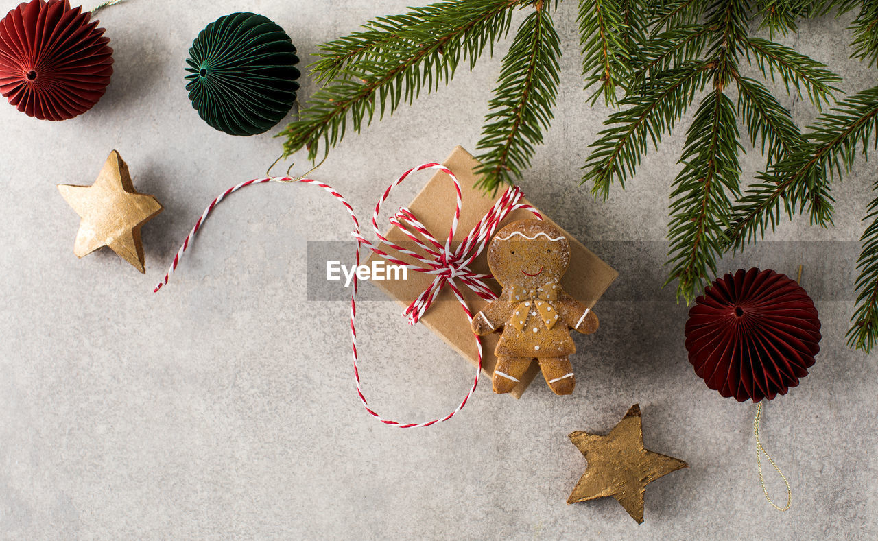 Presents and gingerbread man lie on grey background with christmas tree branches
