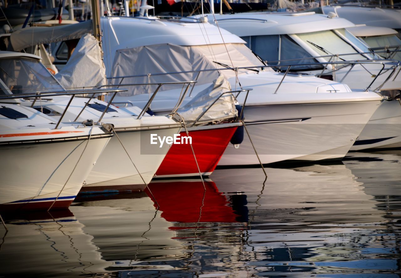 Sailboats moored on harbor against sky